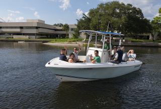 students on a boat with the campus in the background